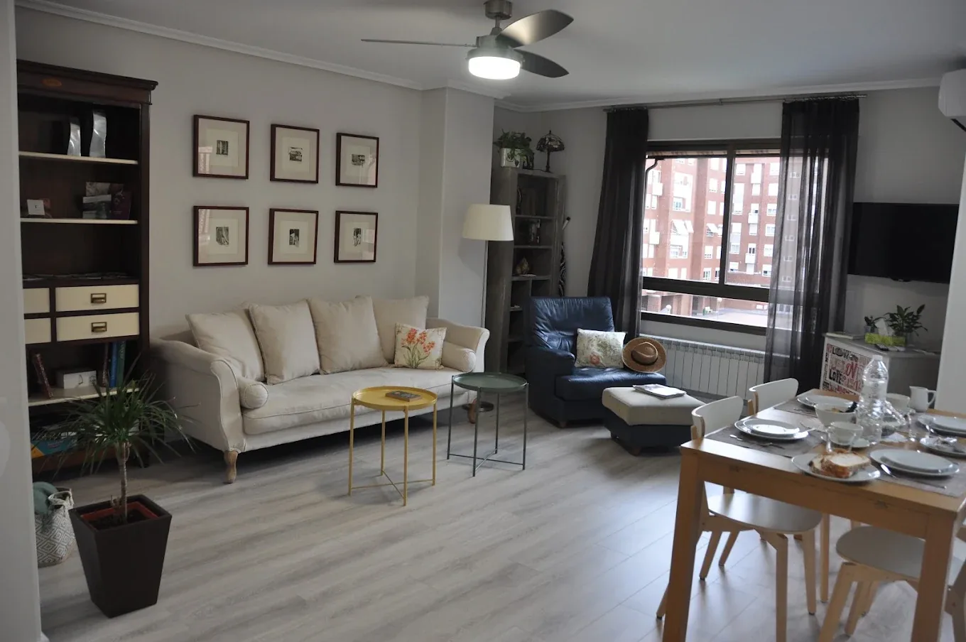 Bright living room with sofa, armchair, large window and dining table